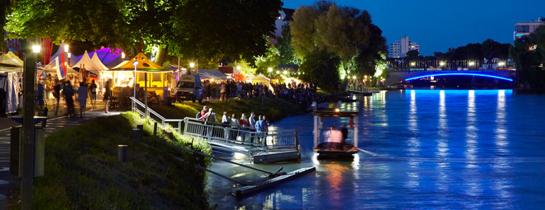 Die Donau und beleuchtete Stände des Donaufests bei Nacht
